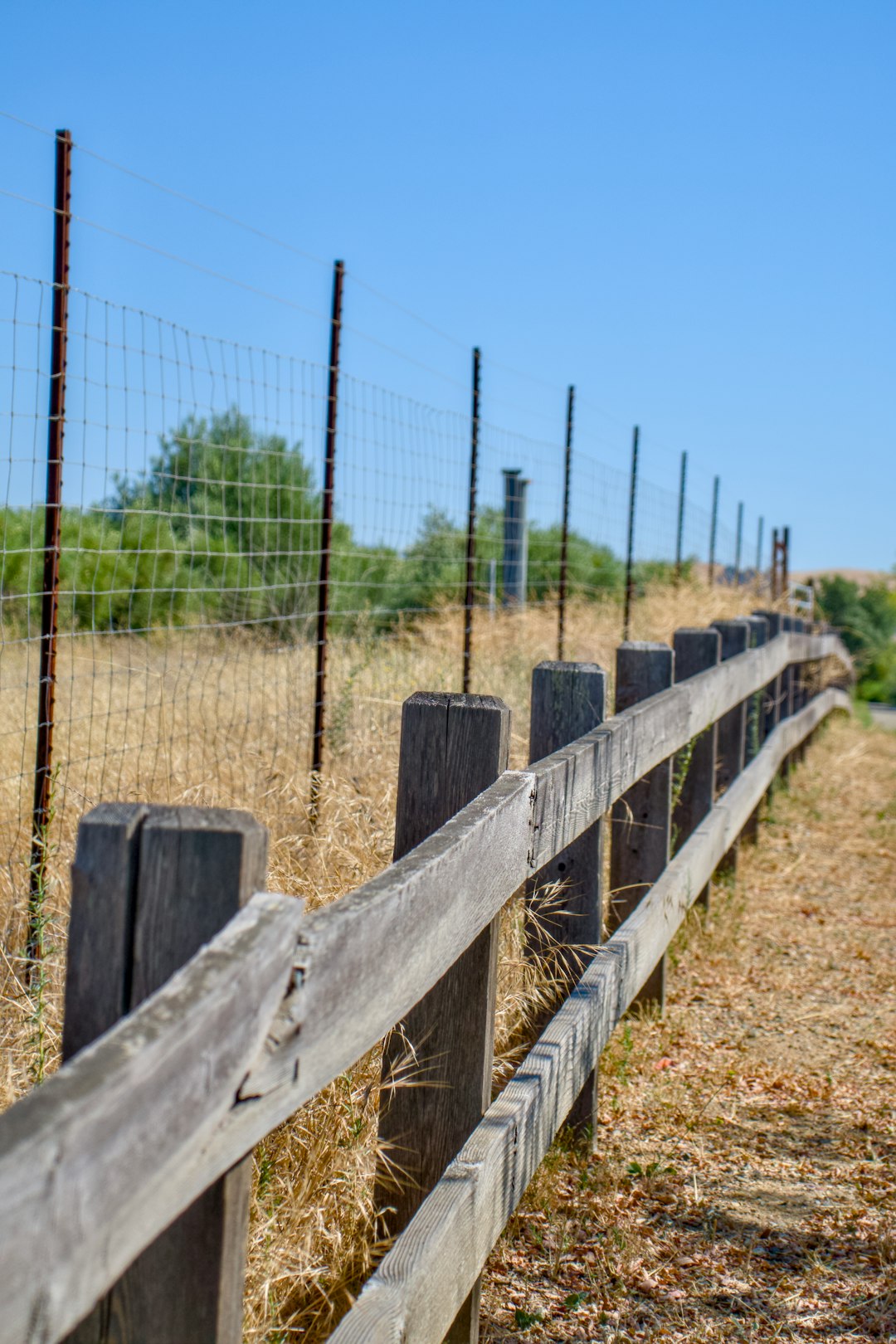 a-wooden-fence-in-the-middle-of-a-field-e-uredn3xio